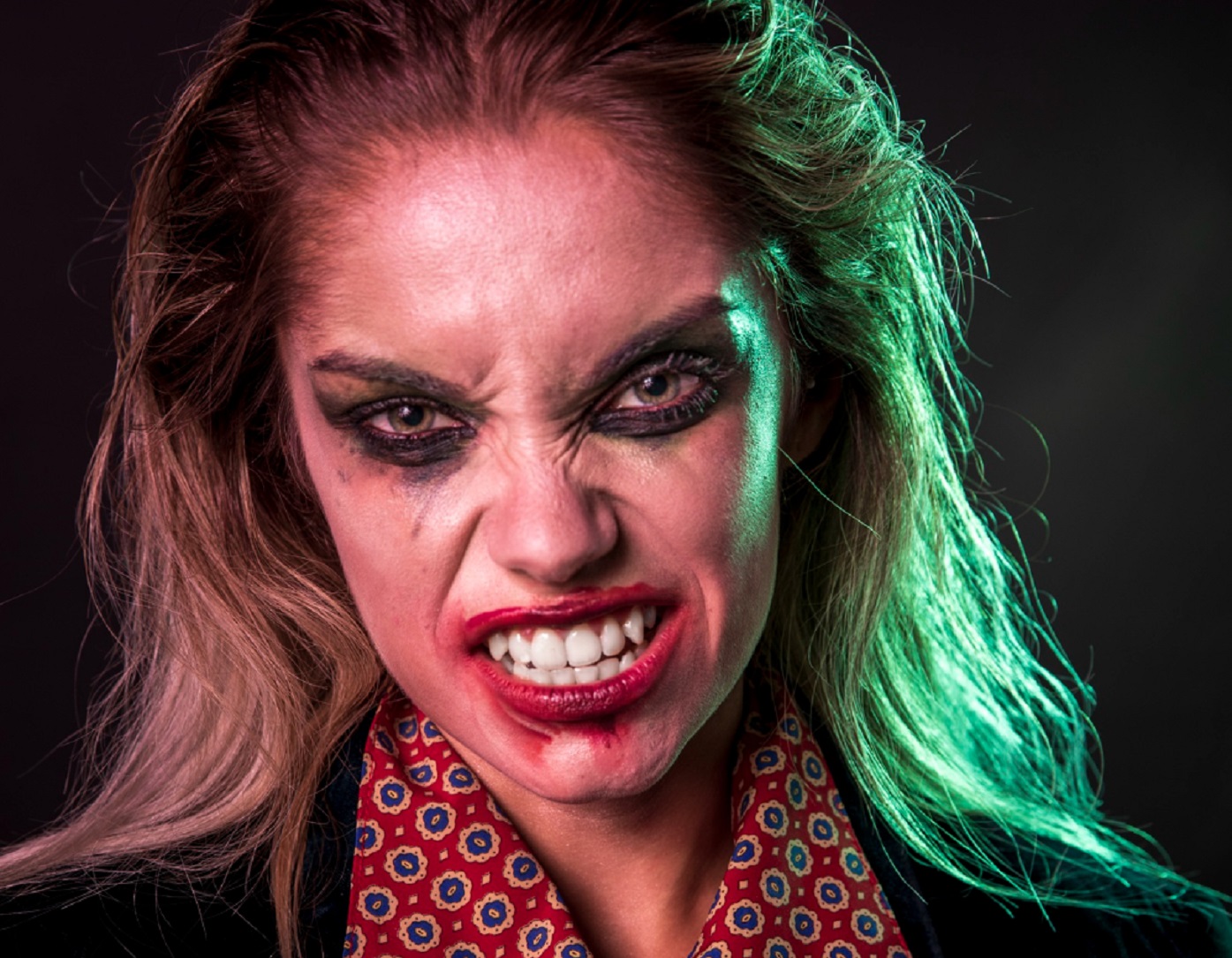 Young woman wearing red shirt and make up ,looking like a vampire.