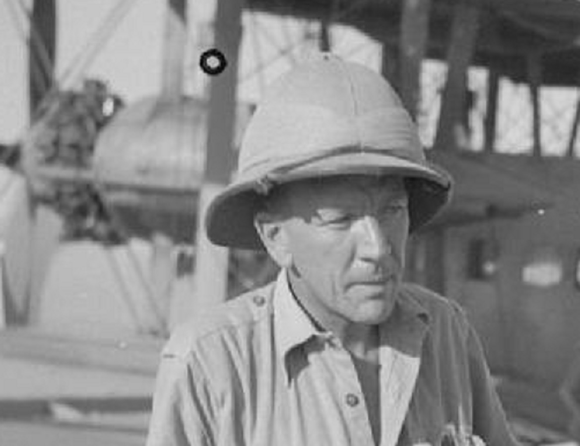 B&W photo of Noel Coward wearing shirt and military helmet - between 1939 and 1945
