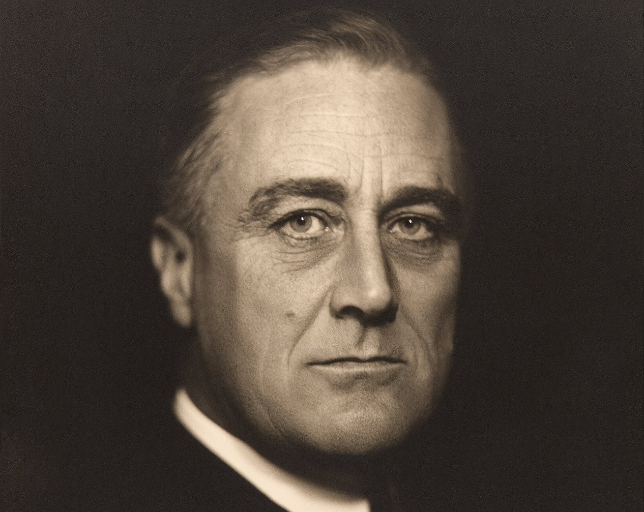 B&W portrait of Franklin D. Roosevelt looking at camera on black background - 1932