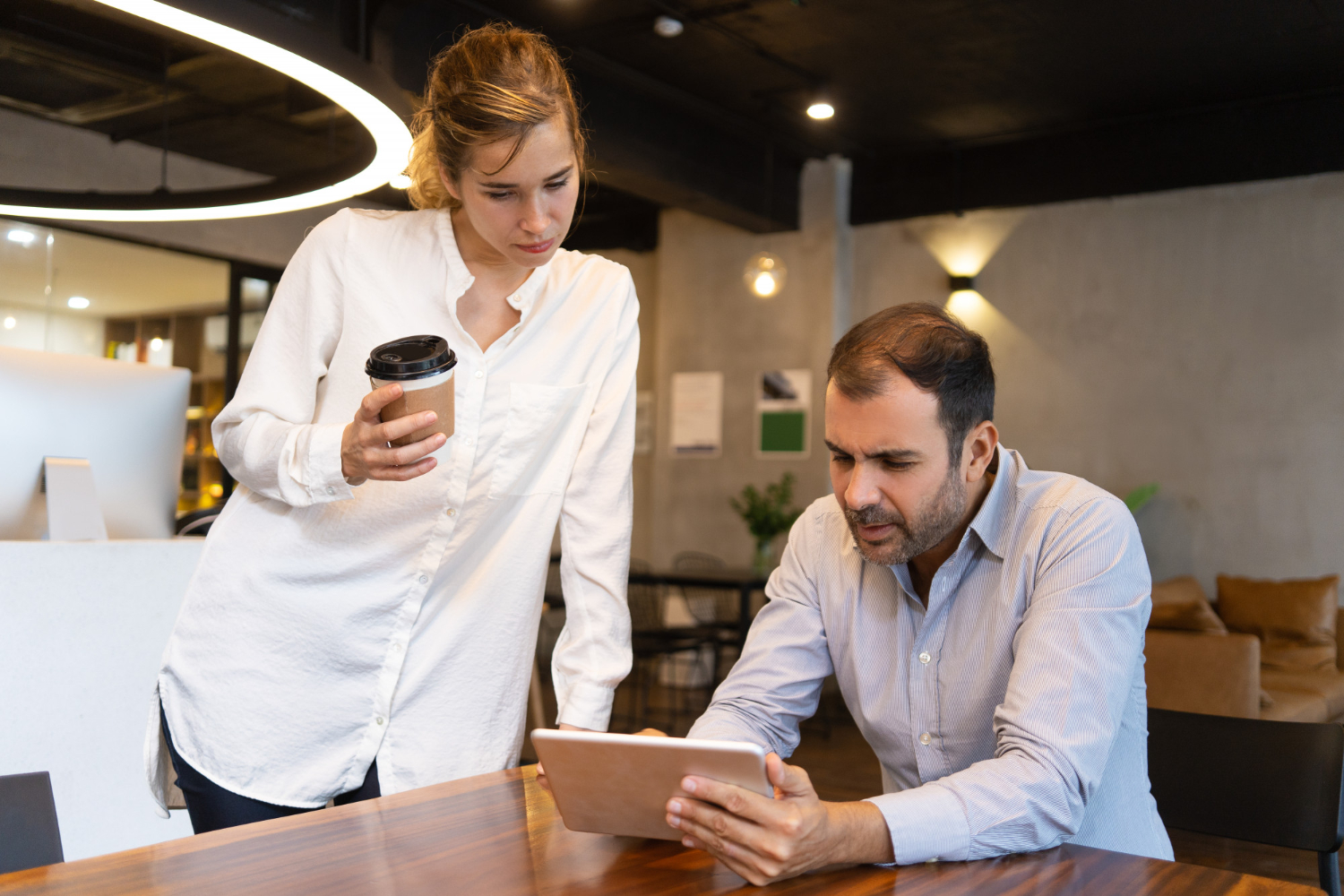 Man and woman are looking at tablet in office.
