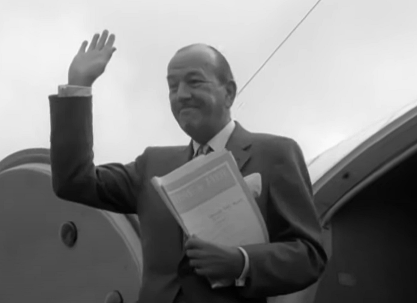 B&W Screenshot: Noel Coward holding a script is smiling outside - from Mad About the Boy: The Noel Coward Story (2023)