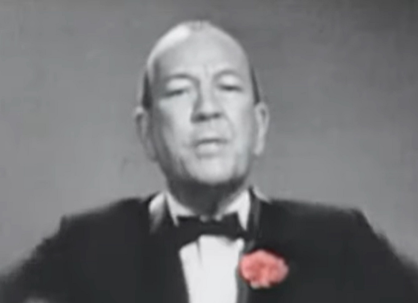 B&W Screenshot: Noel Coward wearing black suit is looking at camera - from Mad About the Boy: The Noel Coward Story (2023)