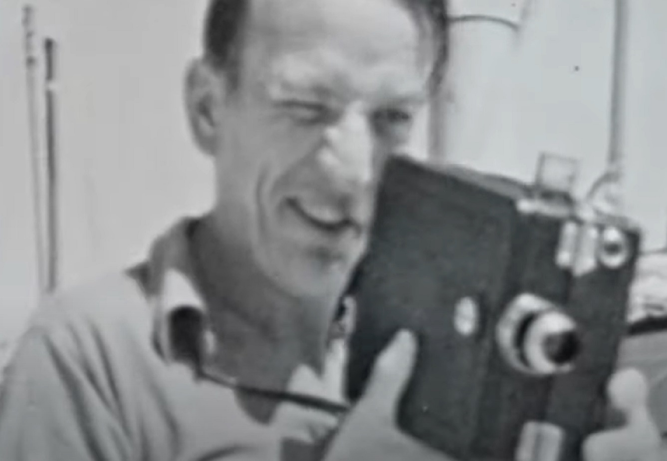 B&W Screenshot: Noel Coward wearing shirt is holding a camera - from Mad About the Boy: The Noel Coward Story (2023)