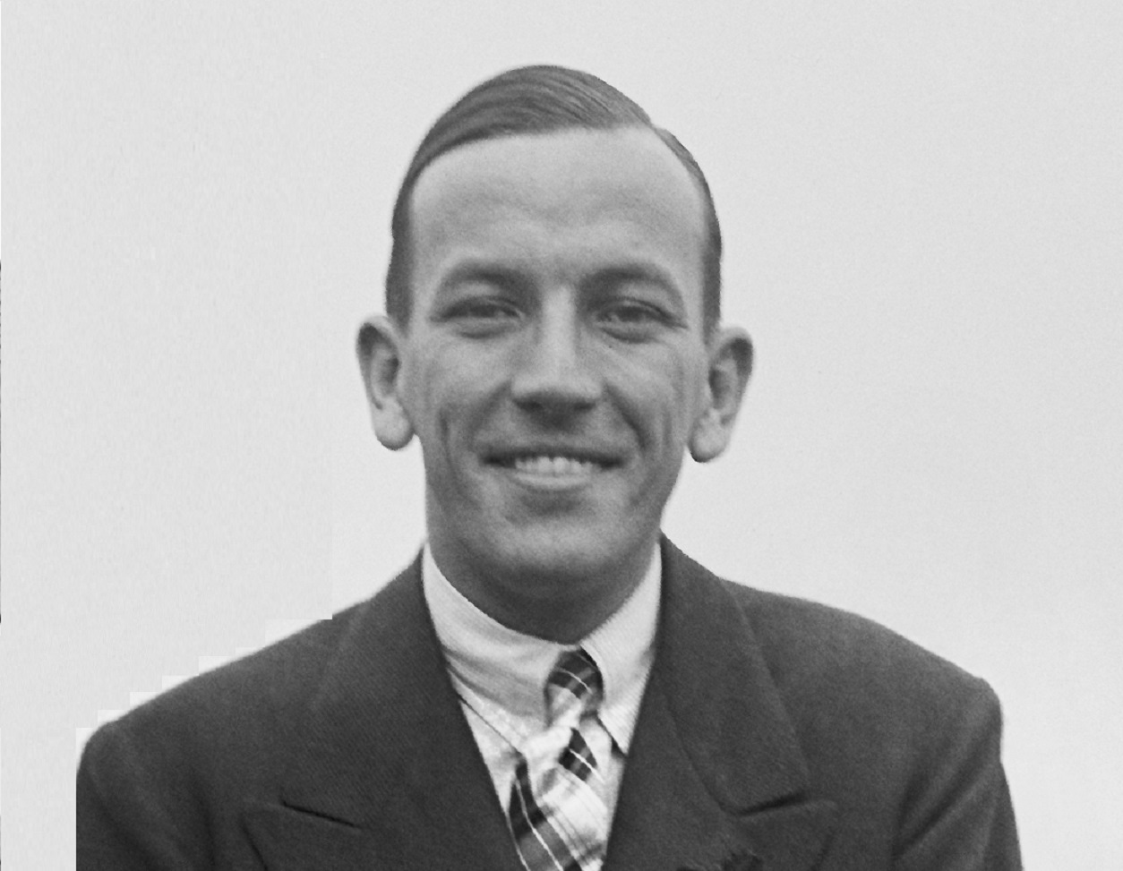 B&W photo of Noel Coward wearing black suit, looking at front and smiling - 1925