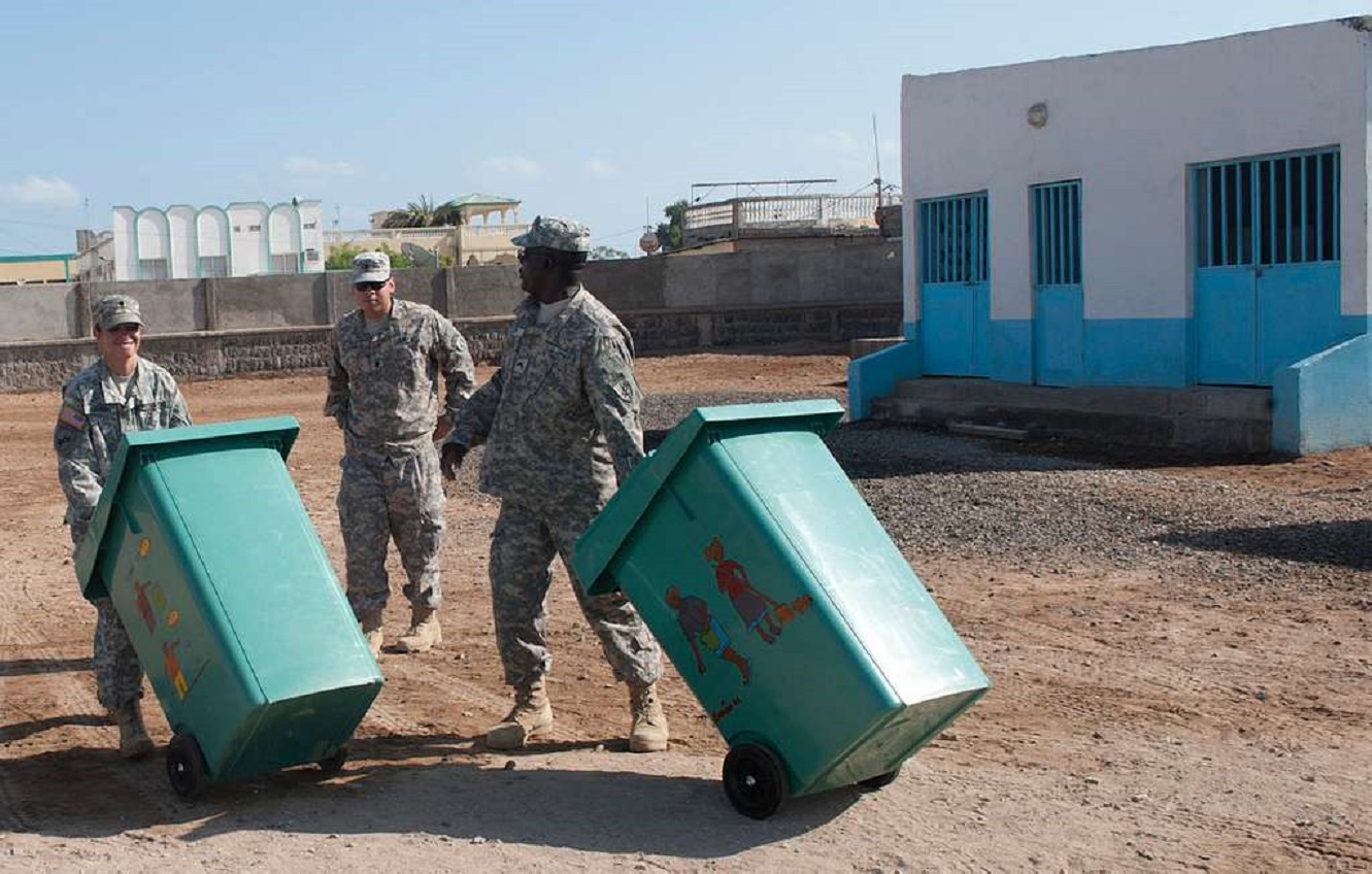 Us Army are taking the trash from trash bin on field.