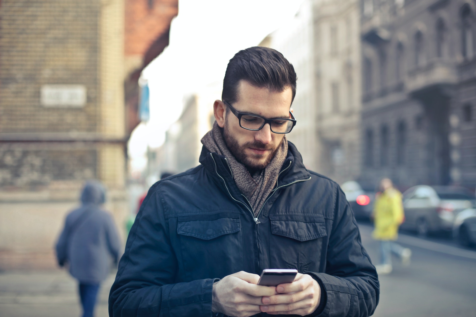 Man Wearing Black Zip Jacket Holding Smartphone