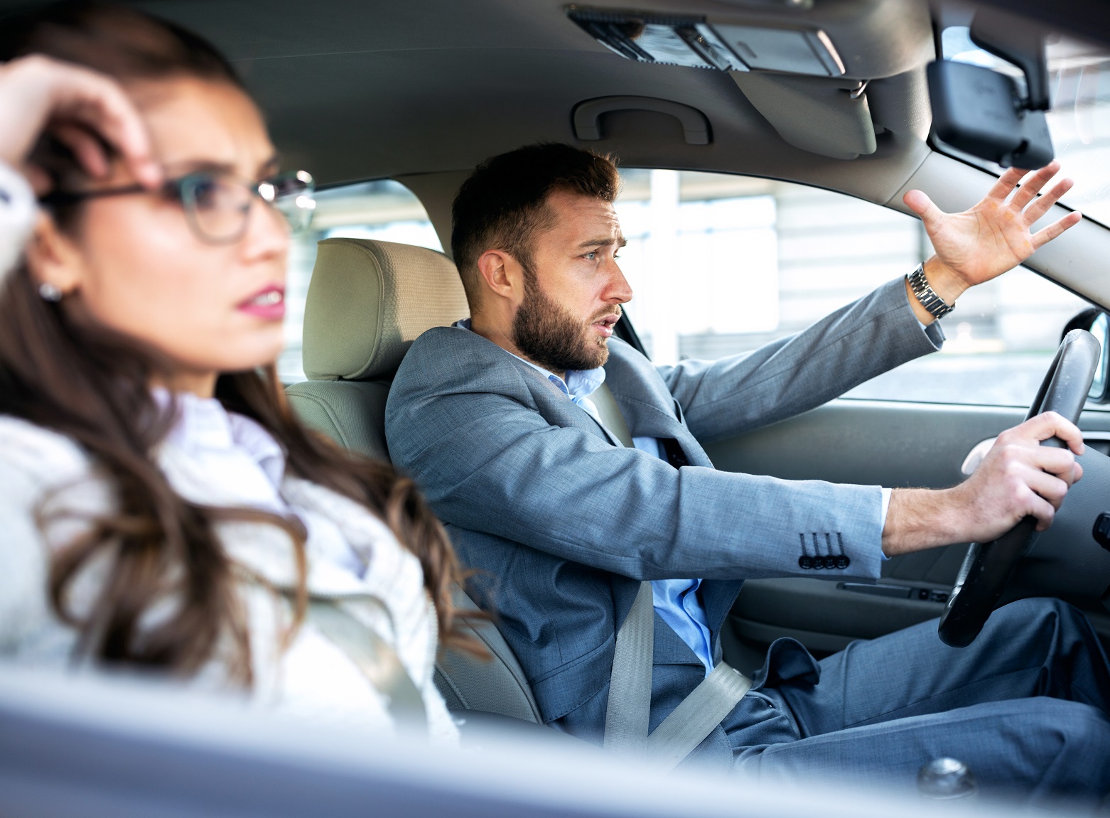 A man and a woman in a stressful situation during car driving with upset faces.