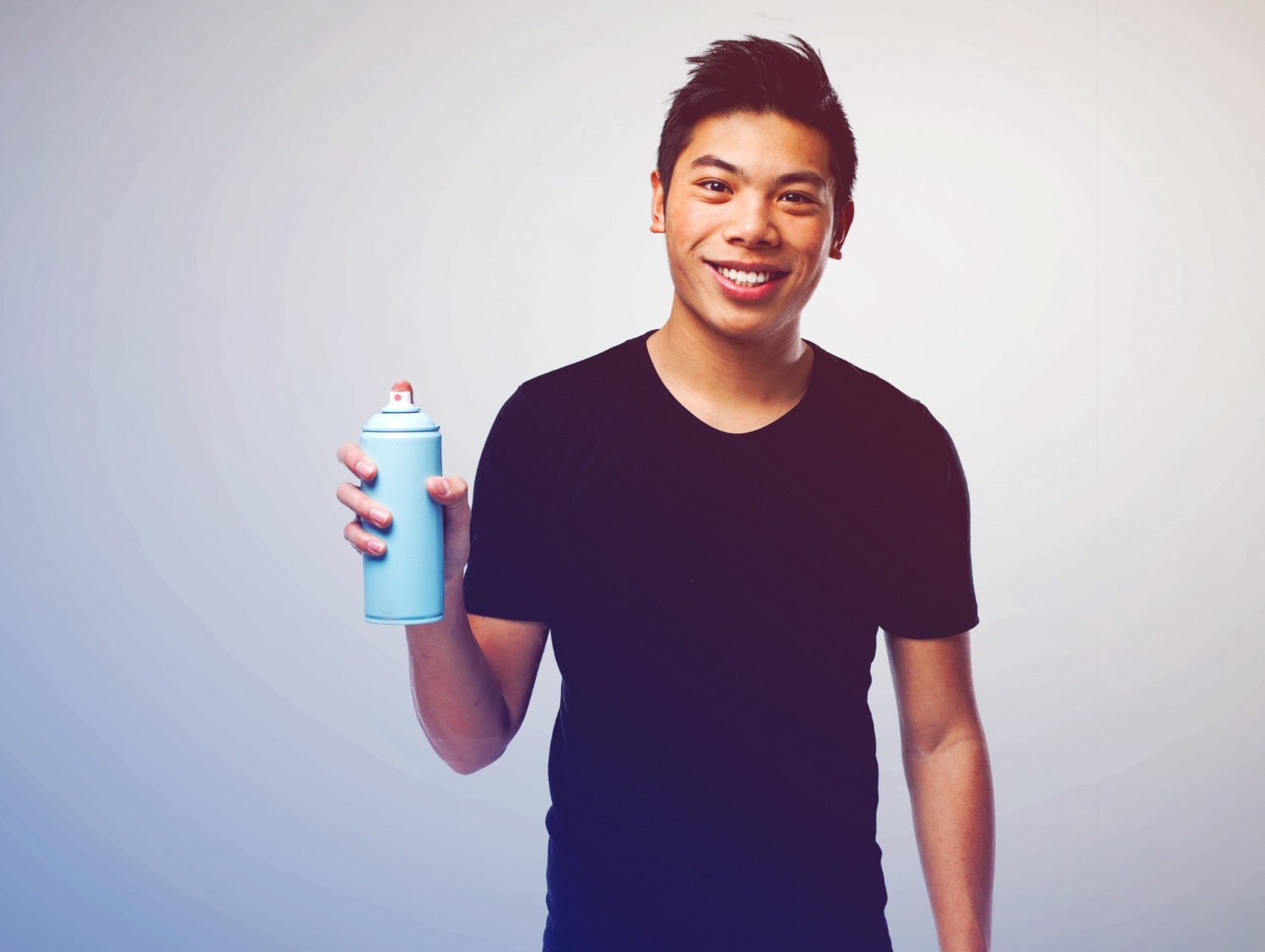 Man is smiling and holding a spray paint in hand.