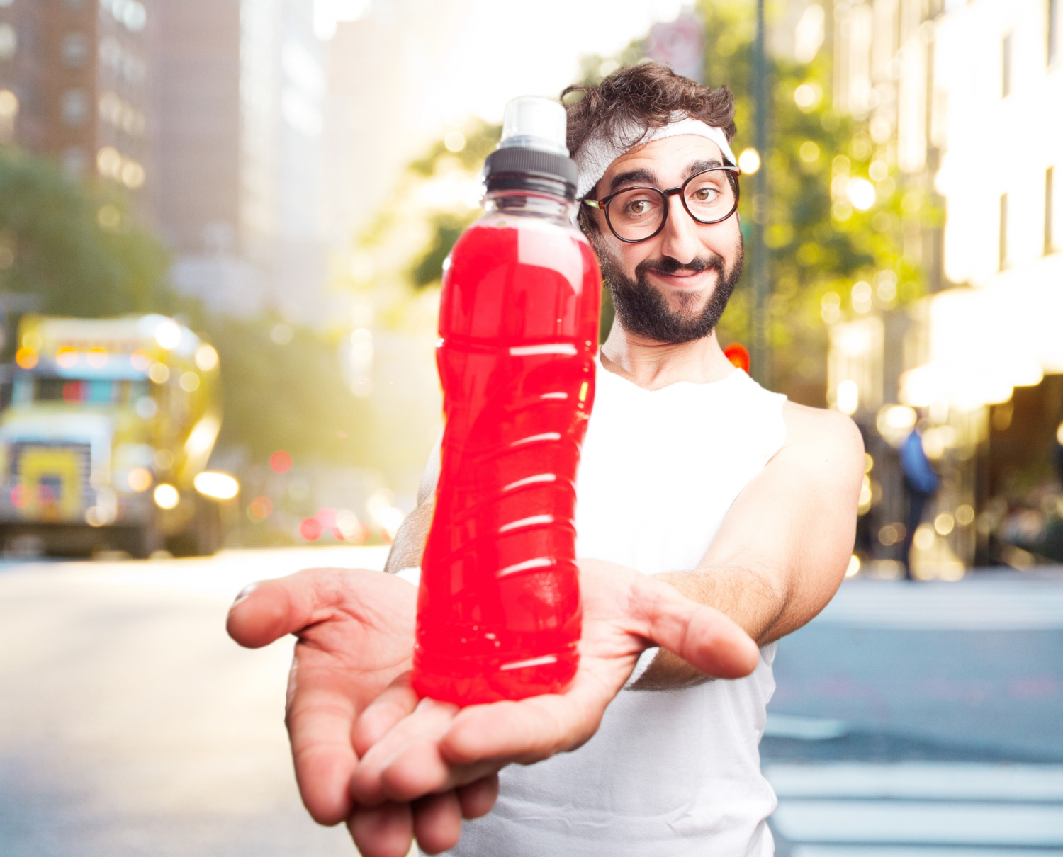 Man is holding a bottle with red soda in hands.