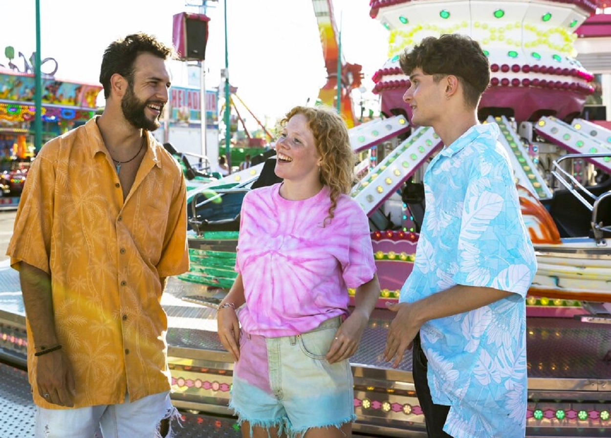 Friends are standing and talking at amusement park.