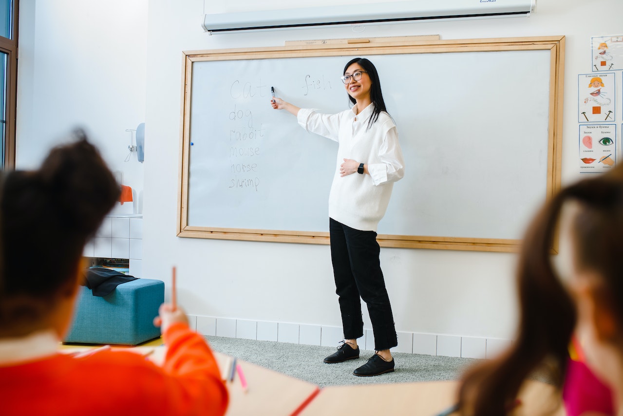 A young woman is teaching in front of the class.