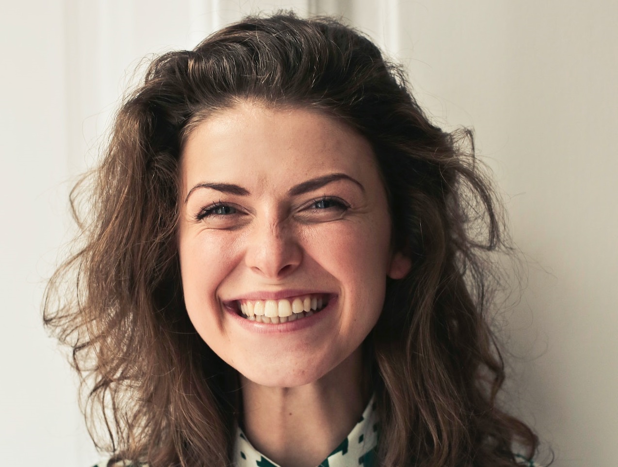 Young woman with long hair is looking and smiling at camera.