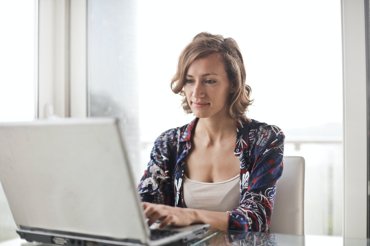 Young woman is working on laptop at her desk.