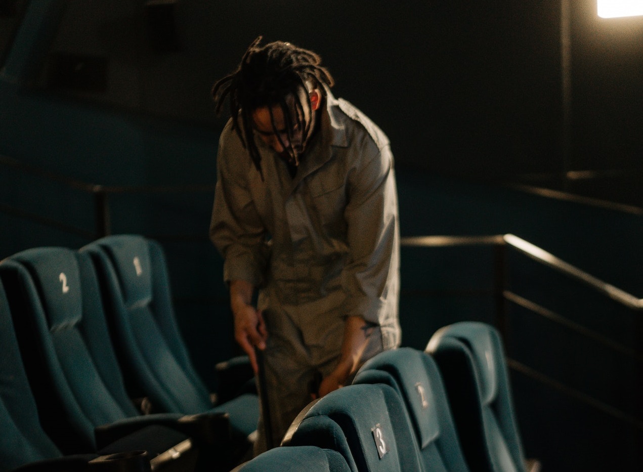 Young man is cleaning the floor in movie theater.