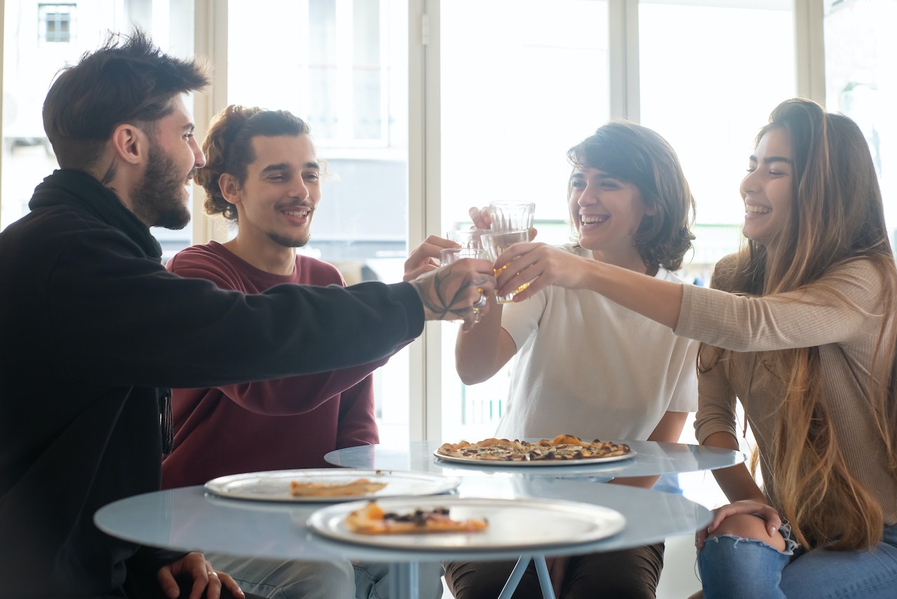 Group of friends having lunch and making a toast at table.