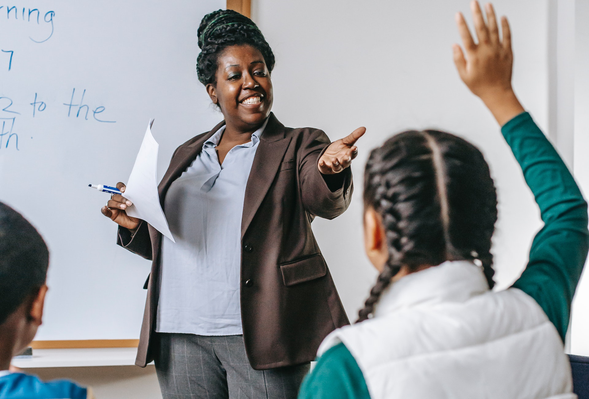 Teacher in front of a board asking students questions