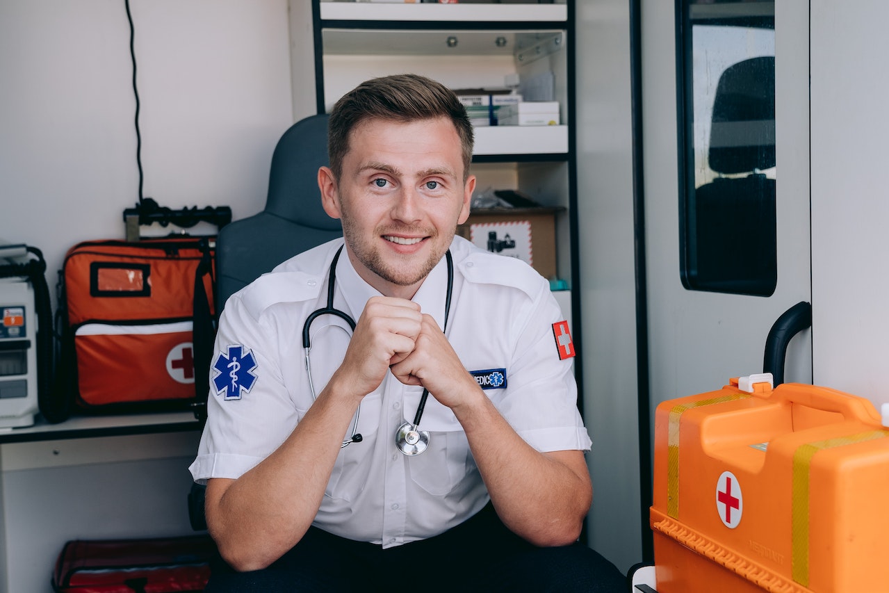 A paramedic is smiling while is sitting inside an ambulance van.