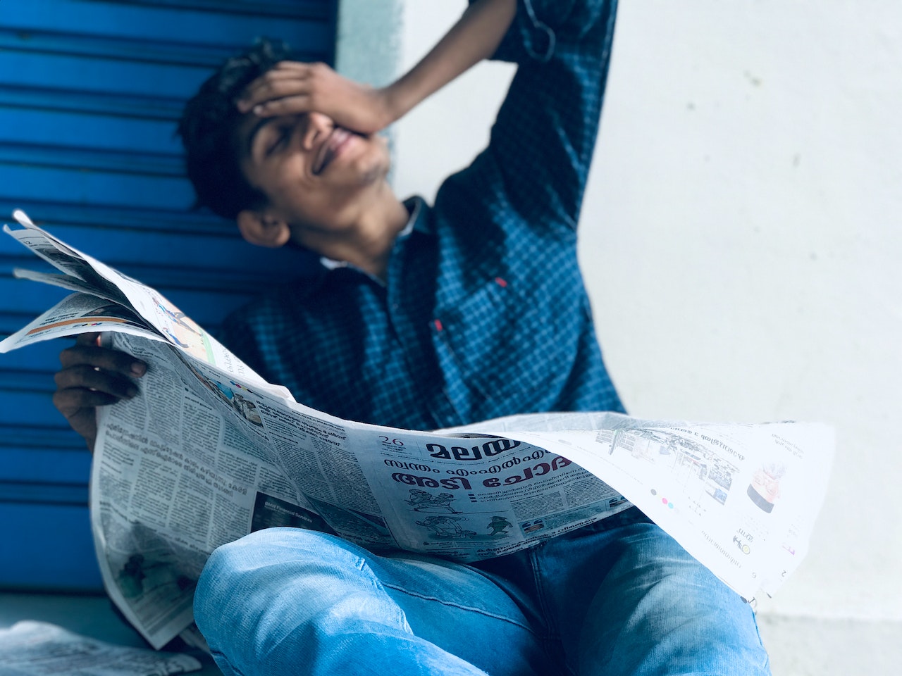 Young man is holding a news paper in his hands.