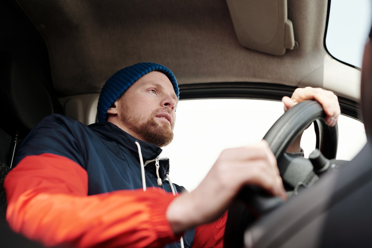 Young man is driving a car and looking at front.