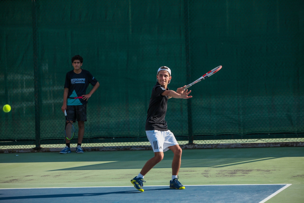 A young man is playing tennis on tennis court.