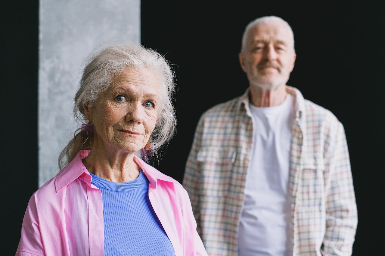 Senior couple are standing and watching at camera with happy faces.