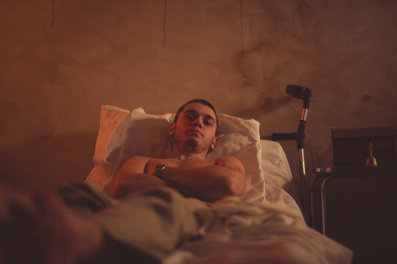 Young patient is lying in hospital bed and looking sad.