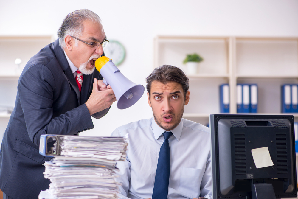 Angry Old boss yelling at young male employee in the office
