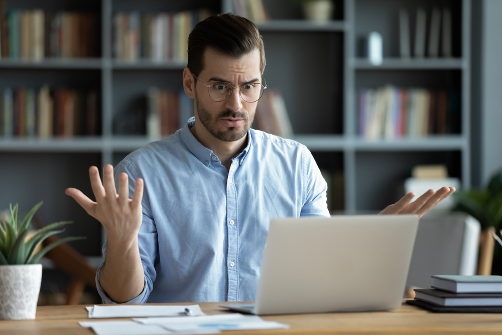 Shocked employee looking at e-mail he got on his laptop