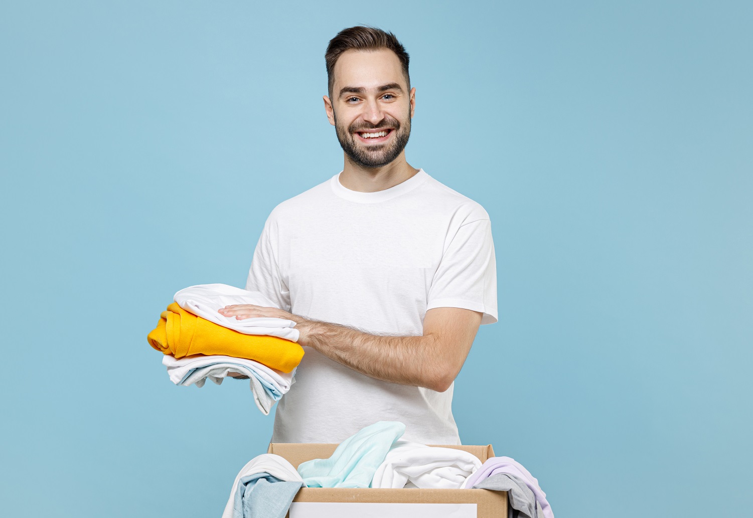 Man in white t-shirt stand near table packing t-shirts in the box.