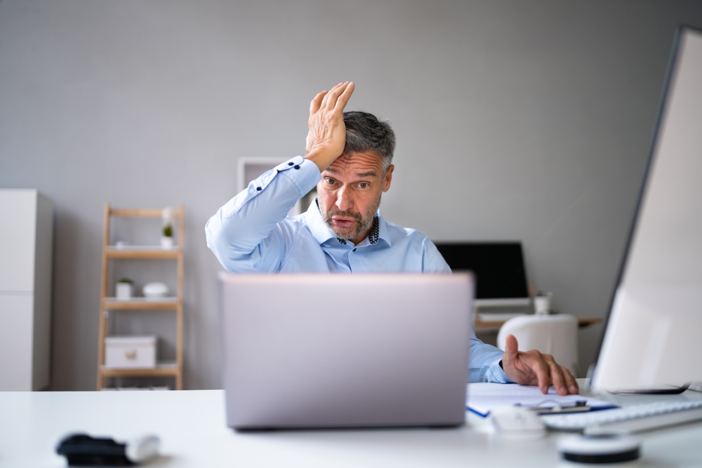 Mature Man confused sitting at desk in front of a computer