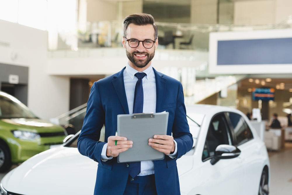 Confident smiling  male  car sales representative  at automobile car dealer shop