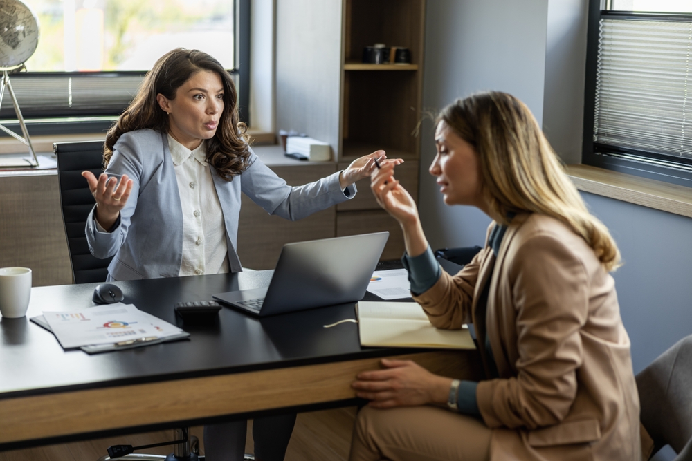 Young ambitious female boss yelling at new unhappy female employee