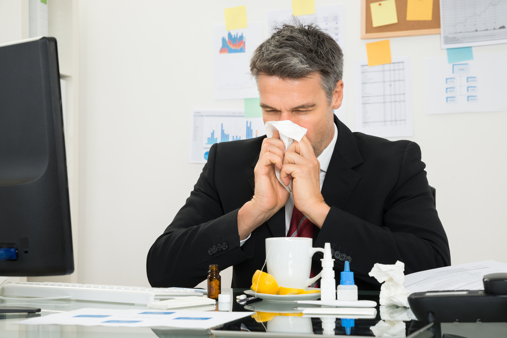 Mature Businessman At Office Desk Blowing His Nose