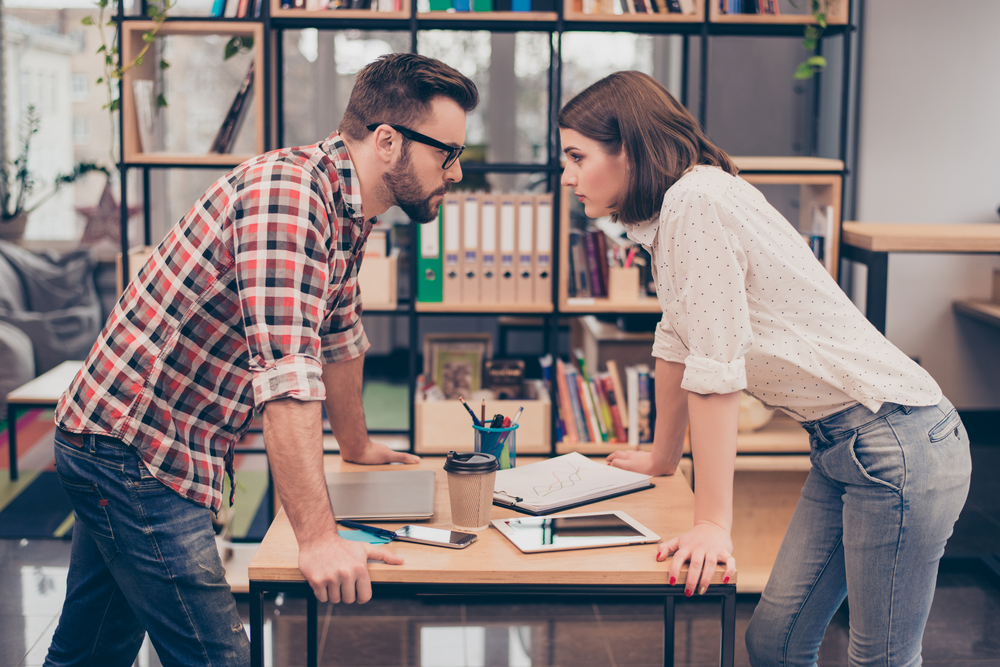 Man and woman colleagues arguing in office