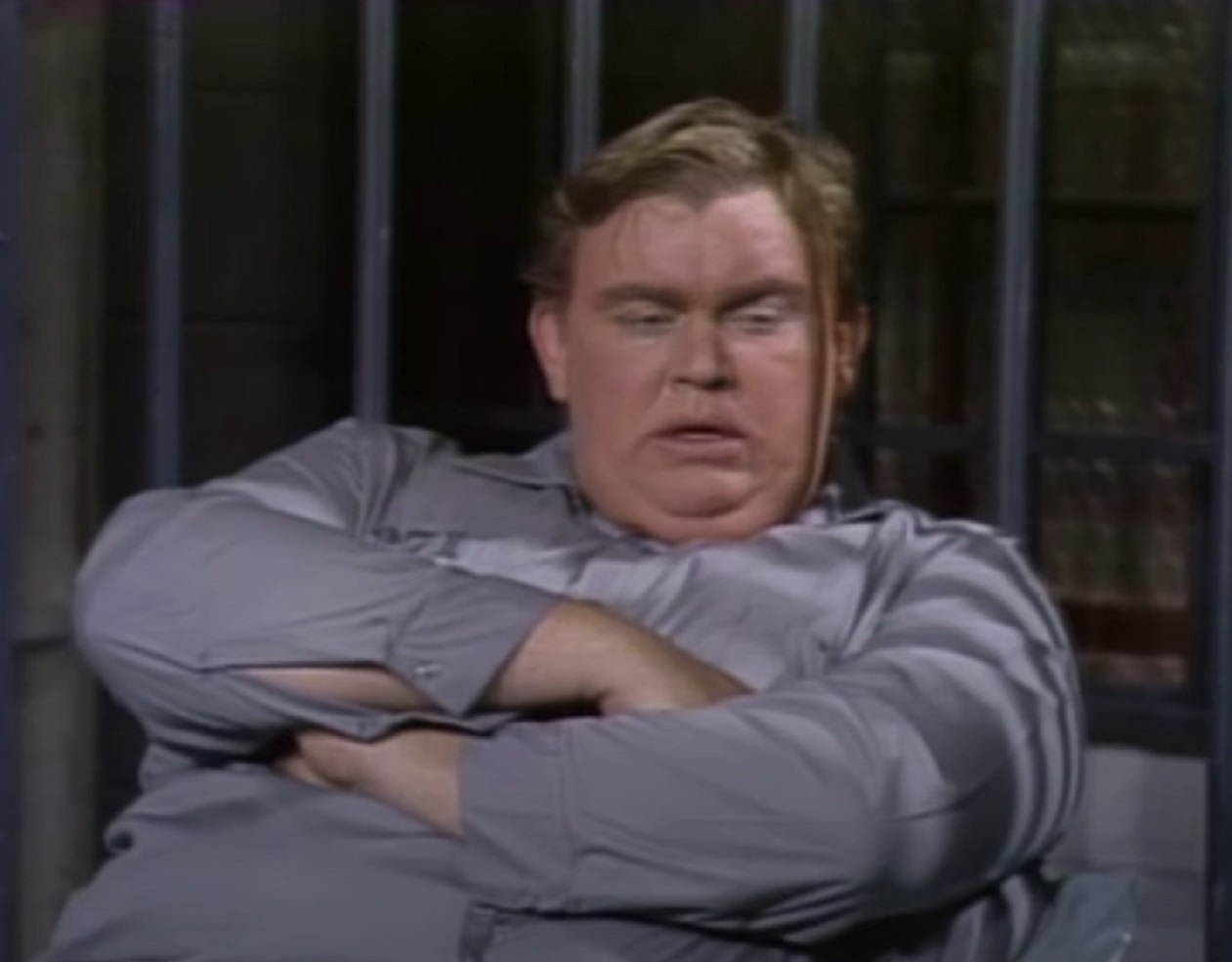 Screenshot :John Candy is seating in jail cell ,crossing his arms - from SNL (1983)