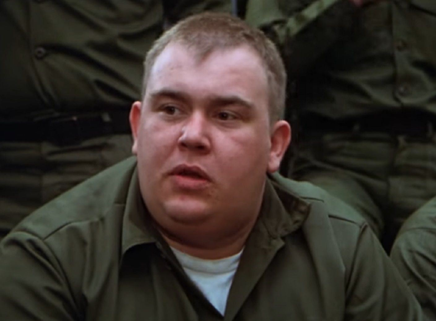Screenshot :John Candy wearing green military uniform is looking at side - from Stripes (1981)