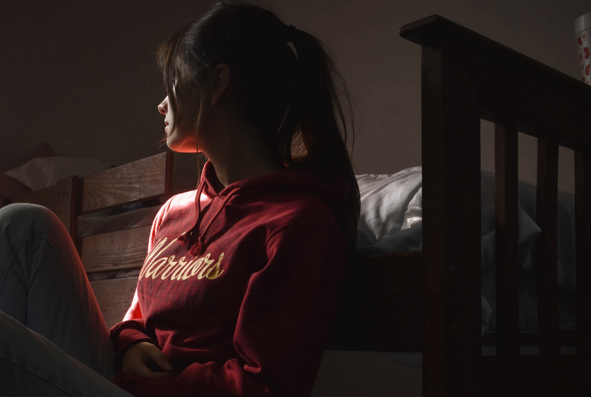 Depressed   woman sitting on floor next to a bed