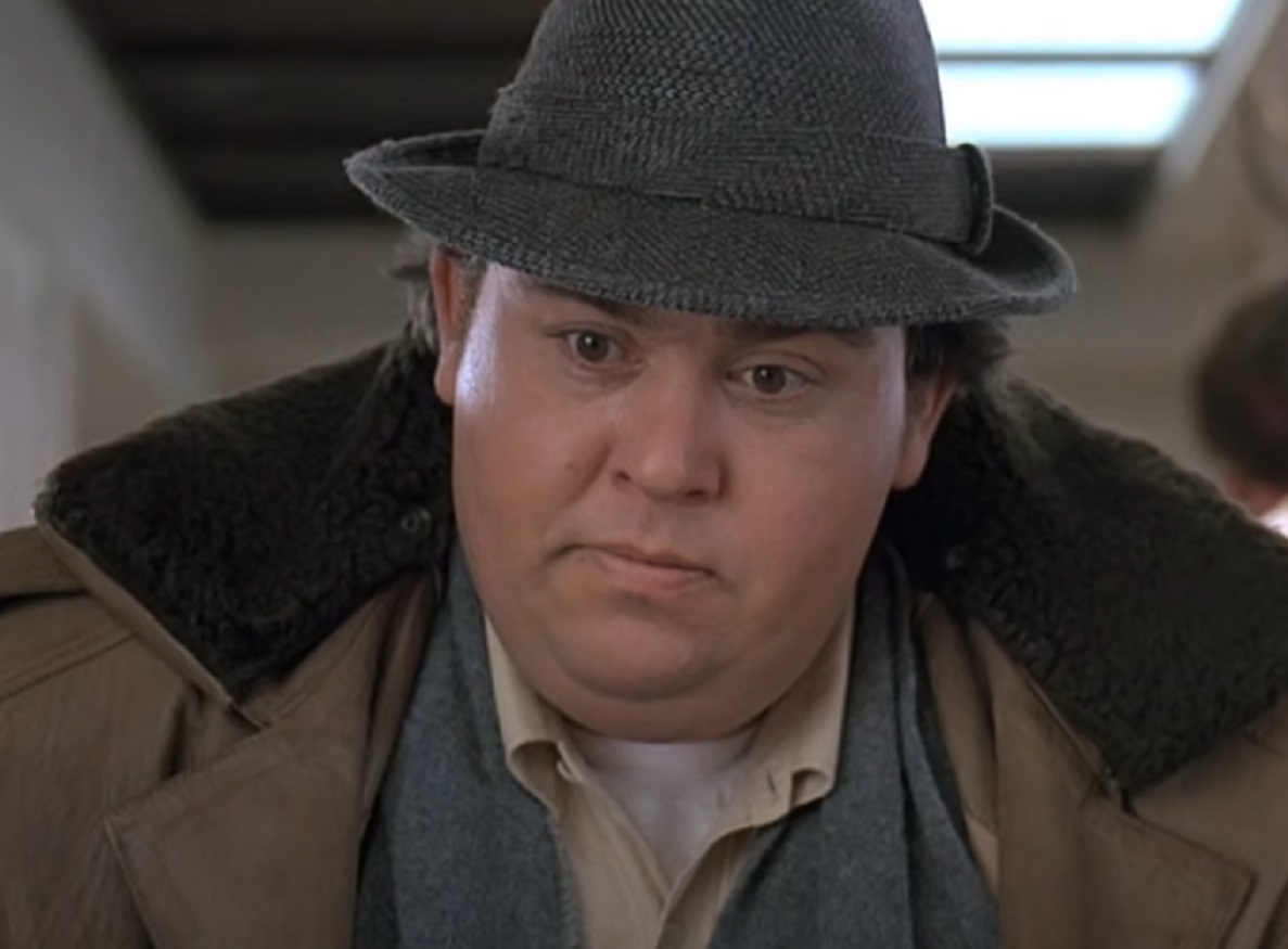 Screenshot :John Candy wearing brown jacket and hat is looking down - from Uncle Buck (1989)