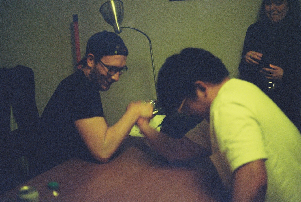 Two man are arm-wrestling on the table in office.
