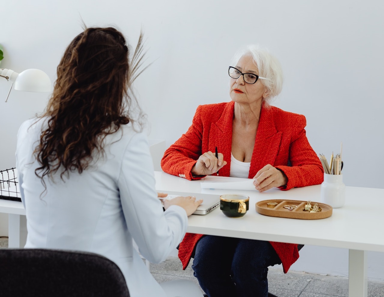 Senior woman wearing red jacket is talking with other woman.