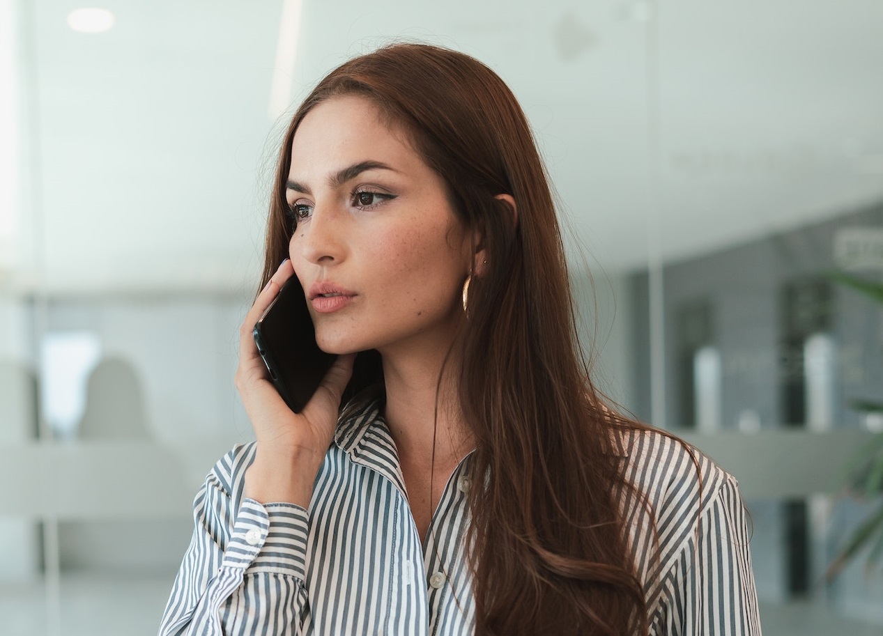 Young woman is looking at side and talking on the phone.