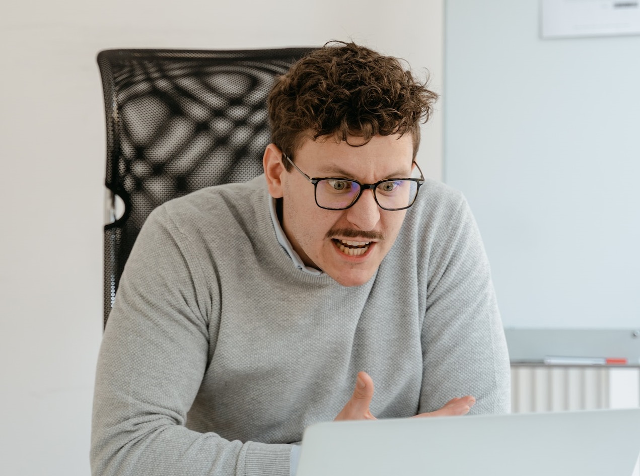 Young man is looking angry in front of a laptop at office.