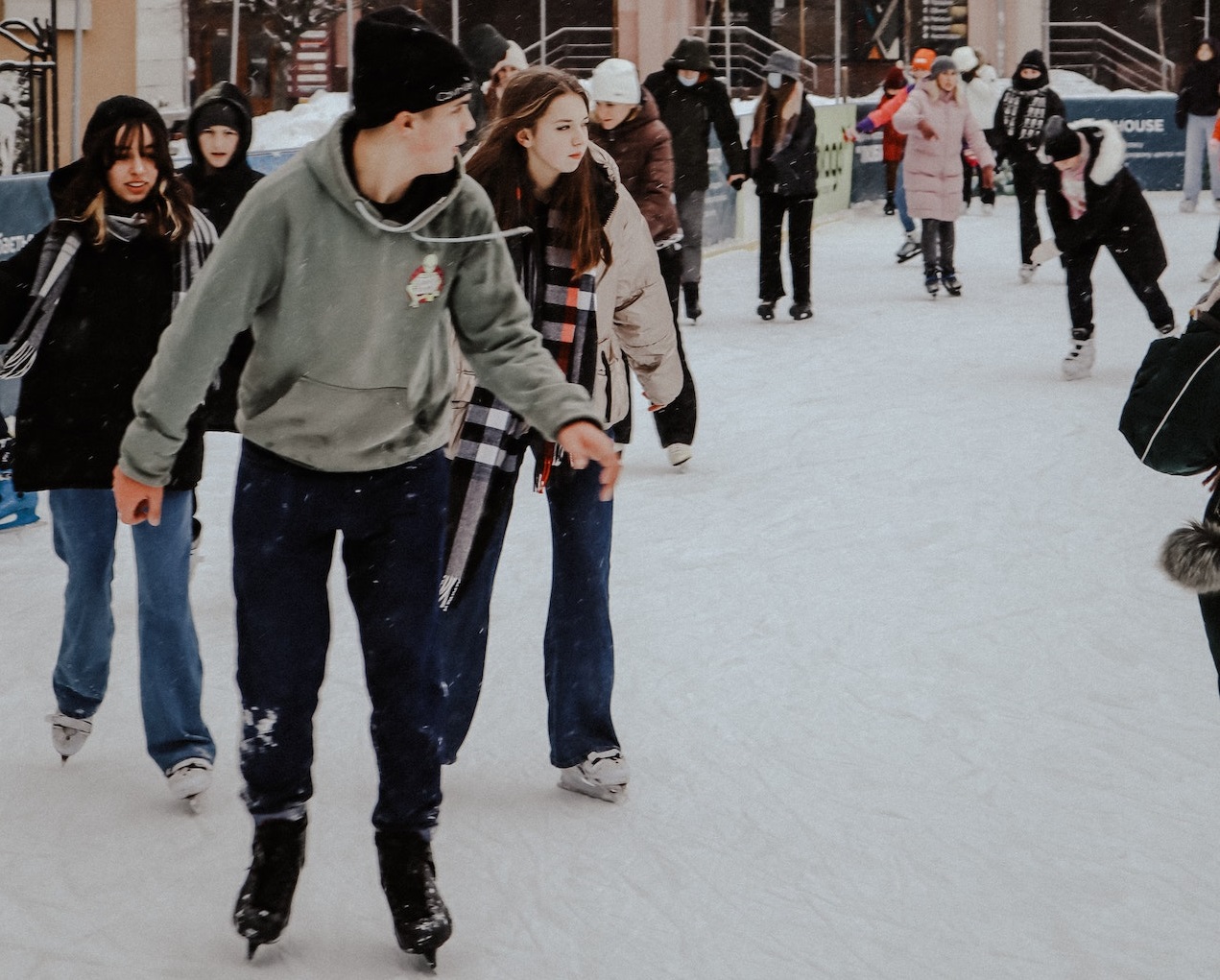 People ice-skating in line near buildings.