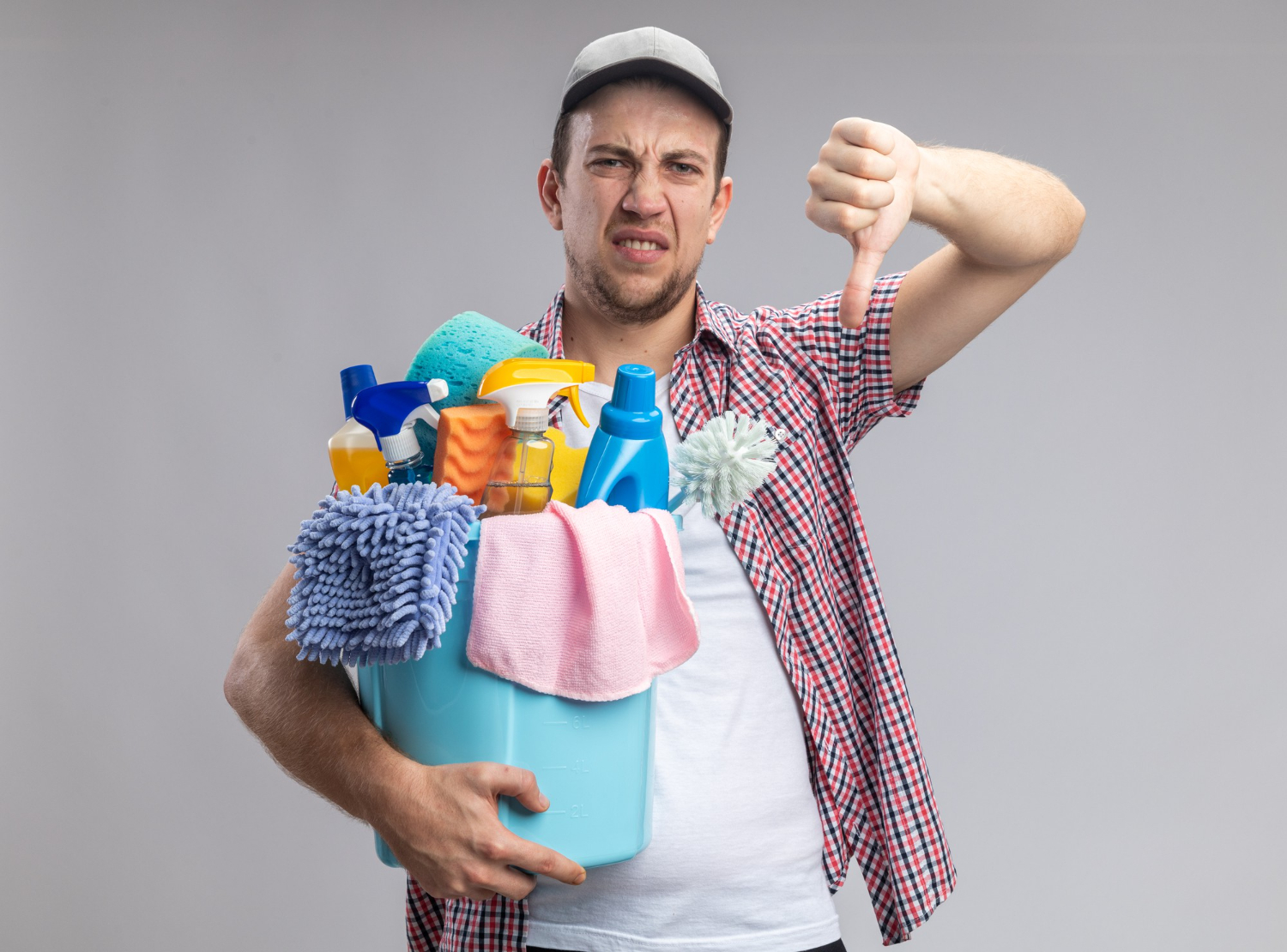 Upset cleaner wearing cap holding bucket with cleaning tools showing thumb down.