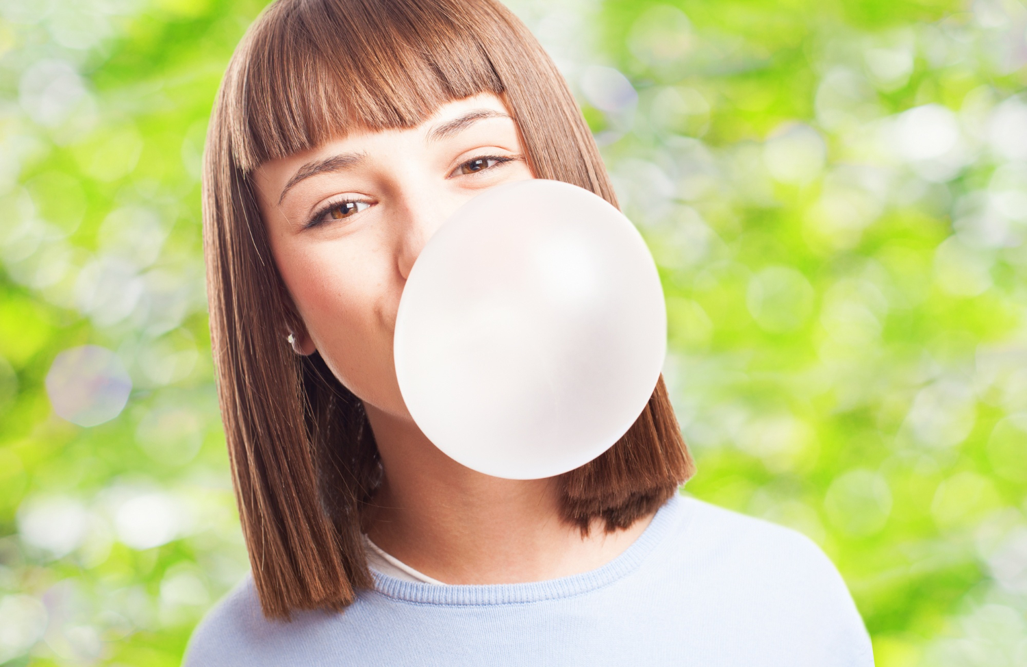 Young girl is playing with bubble gum in her mouth.