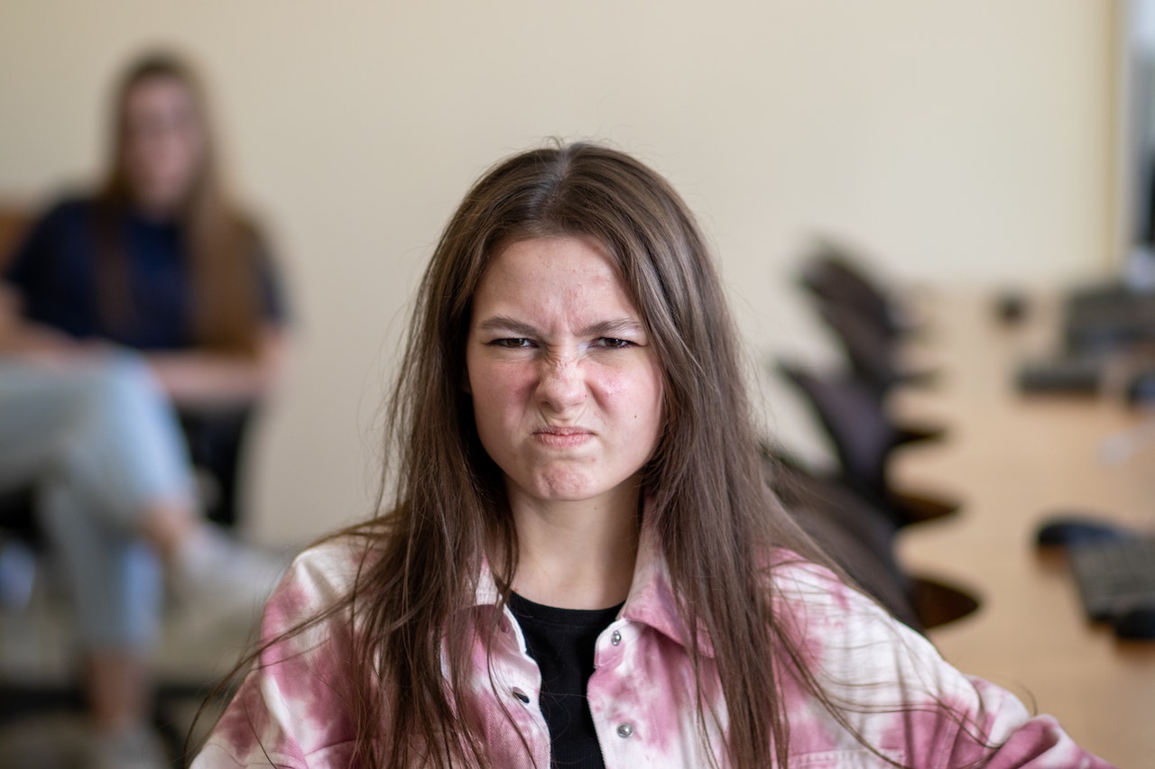 Young girl with messy hair is making a angry face at school.