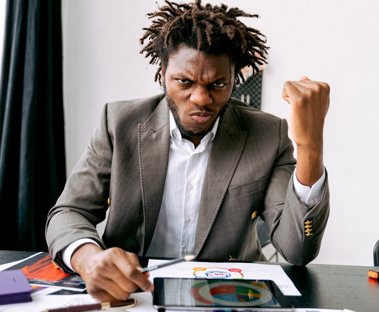 Young man is seating on his desk with upset face.