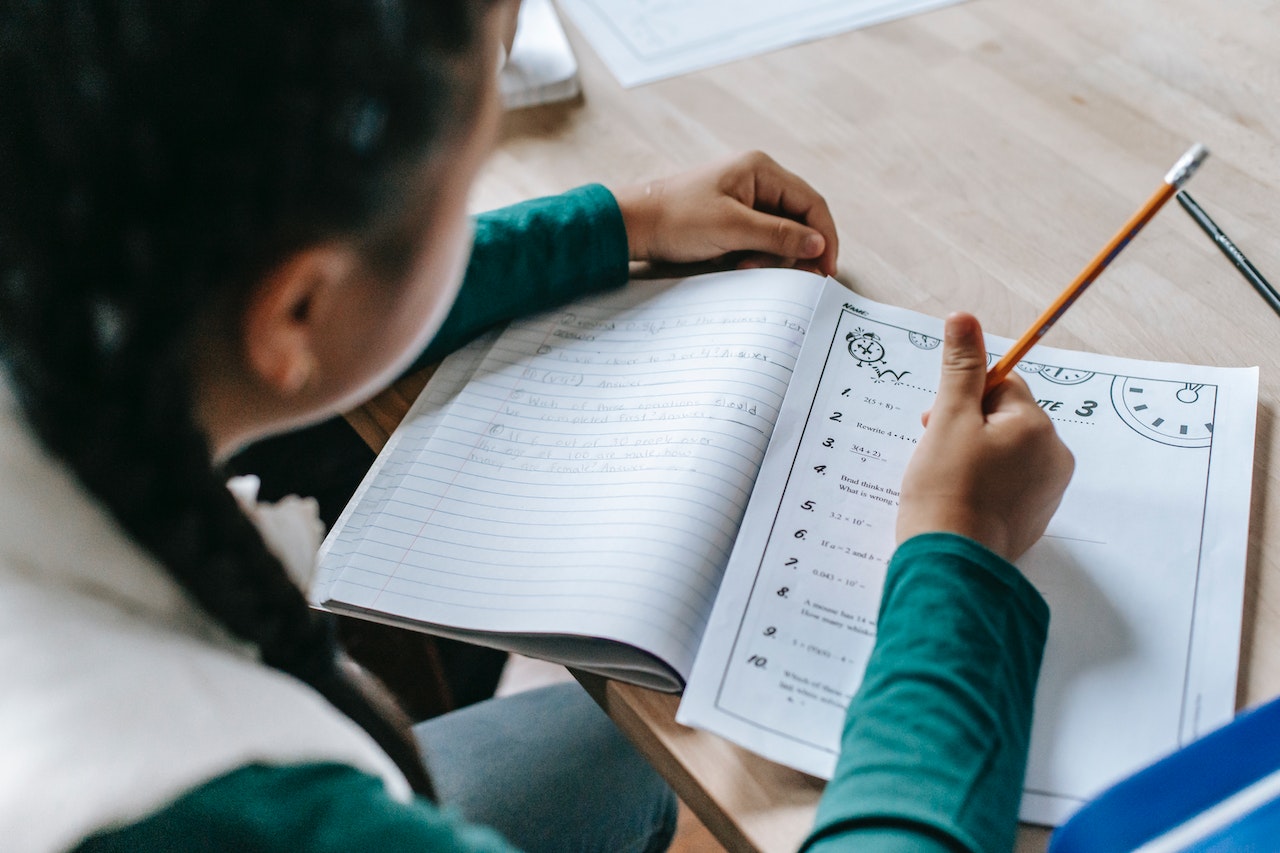 Girl is doing a homework and taking notes in notebook at school.