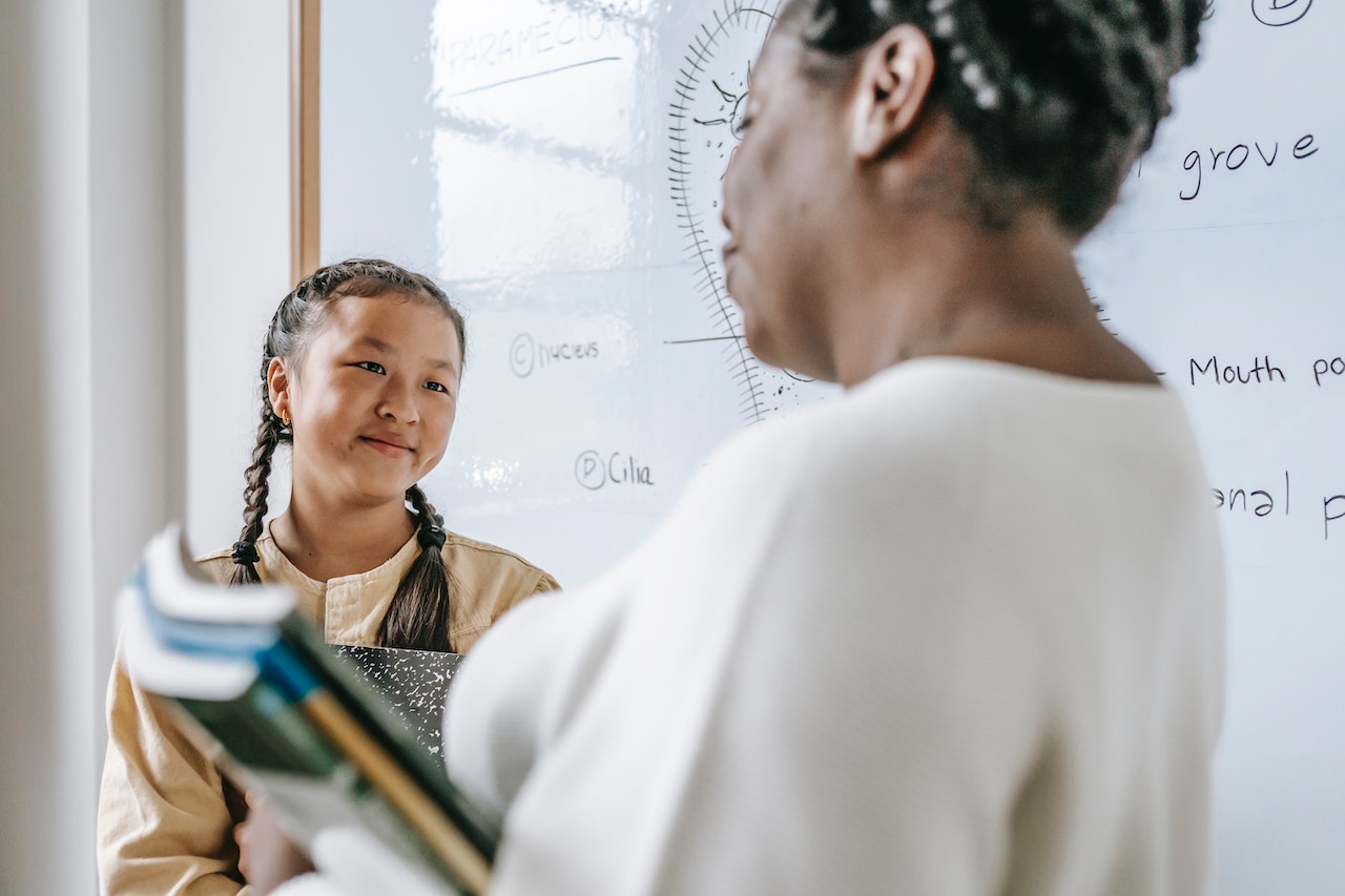 Teacher is talking with young student at class.
