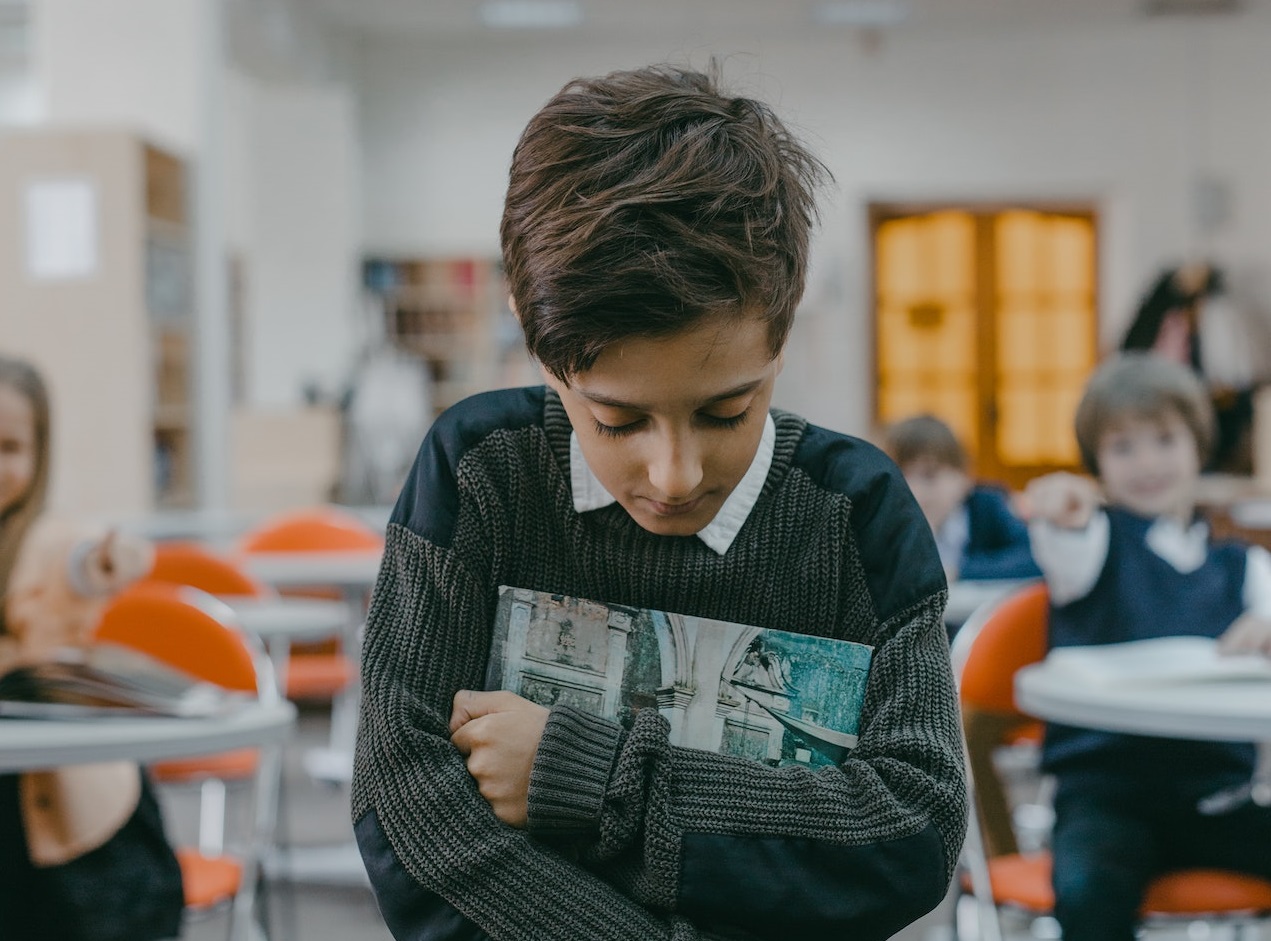 Sad kid is leaving the classroom ,looking down.